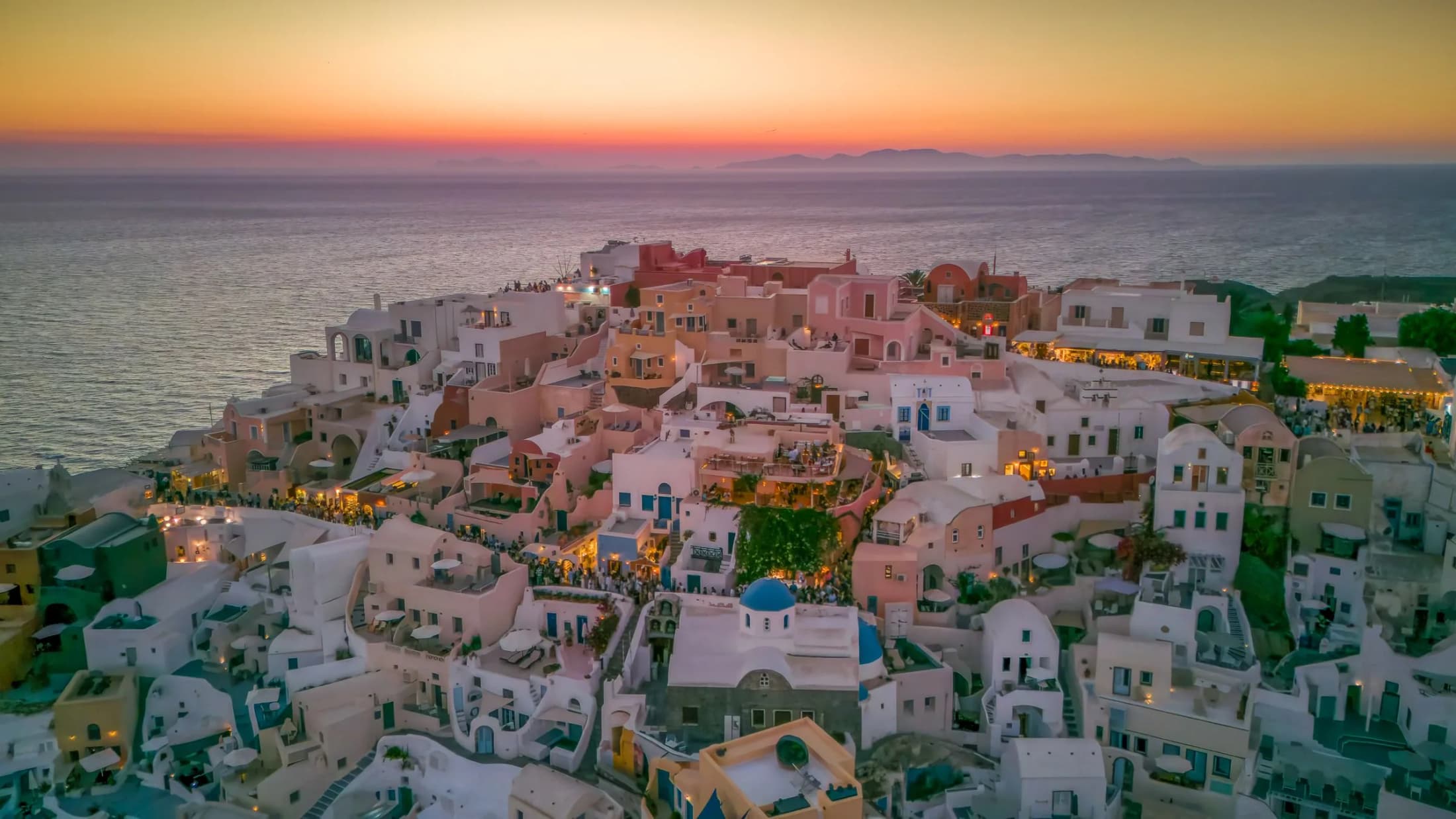 Whitewashed houses of Oia, Santorini, glowing at dusk above the caldera