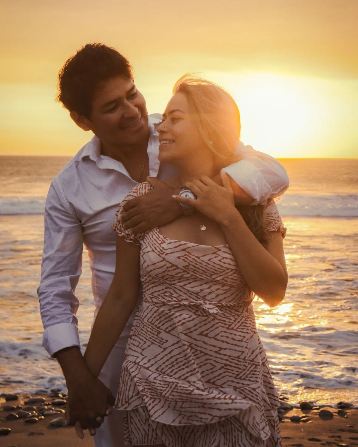 A couple embracing on a beach as the sun sets