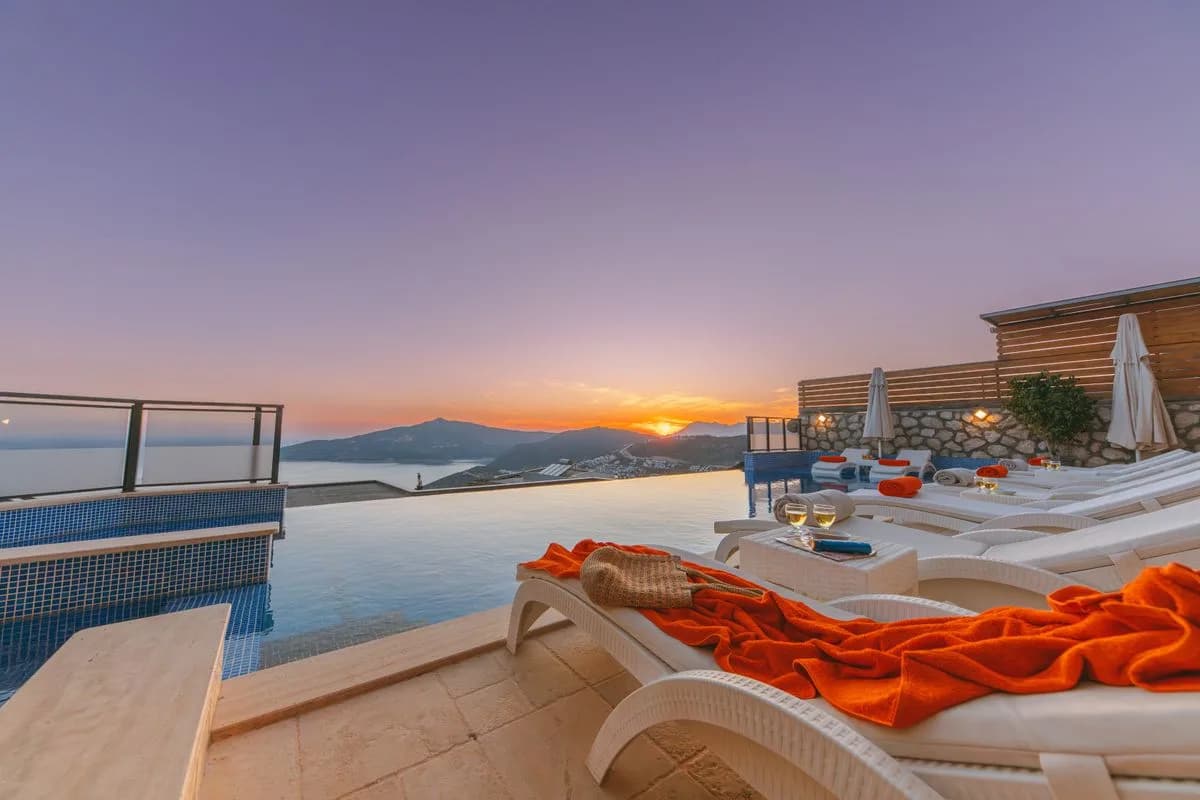 Loungers beside a rooftop infinity pool at sunset